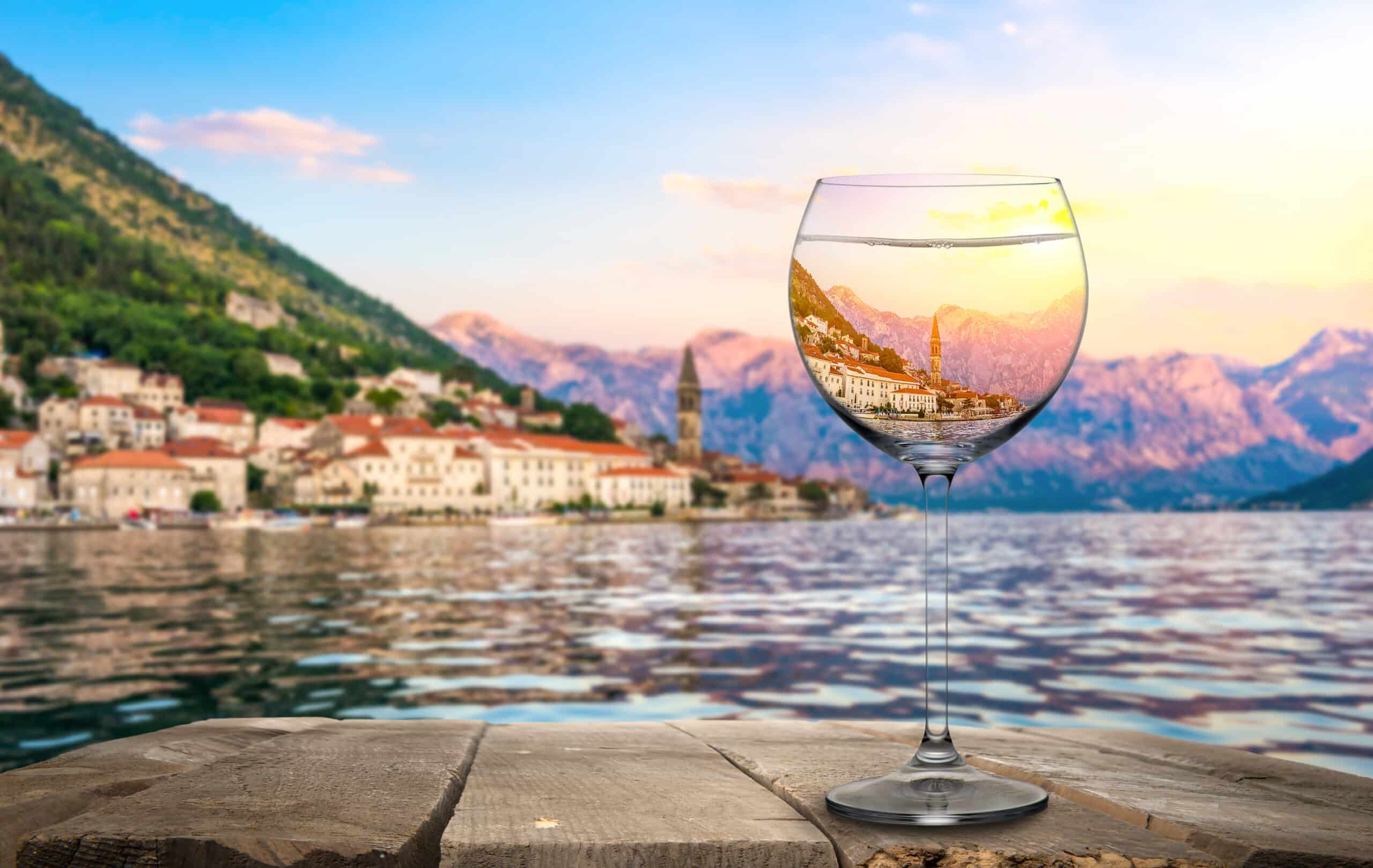 Wineglass on old wooden table on a background of Perast, Montenegro
