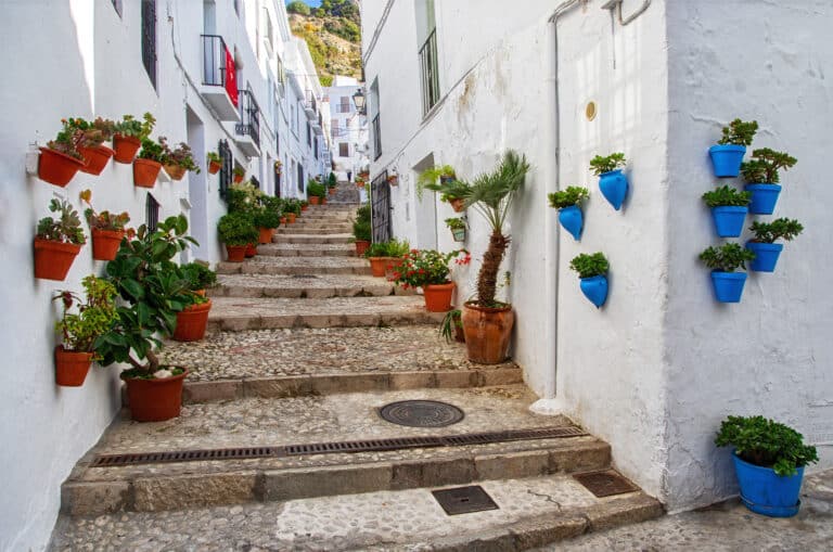 Street in Pueblos blancos in Spain. Village called Frigiliana. Typical aisle full of flower pots between white houses in Andalusia, Spain.