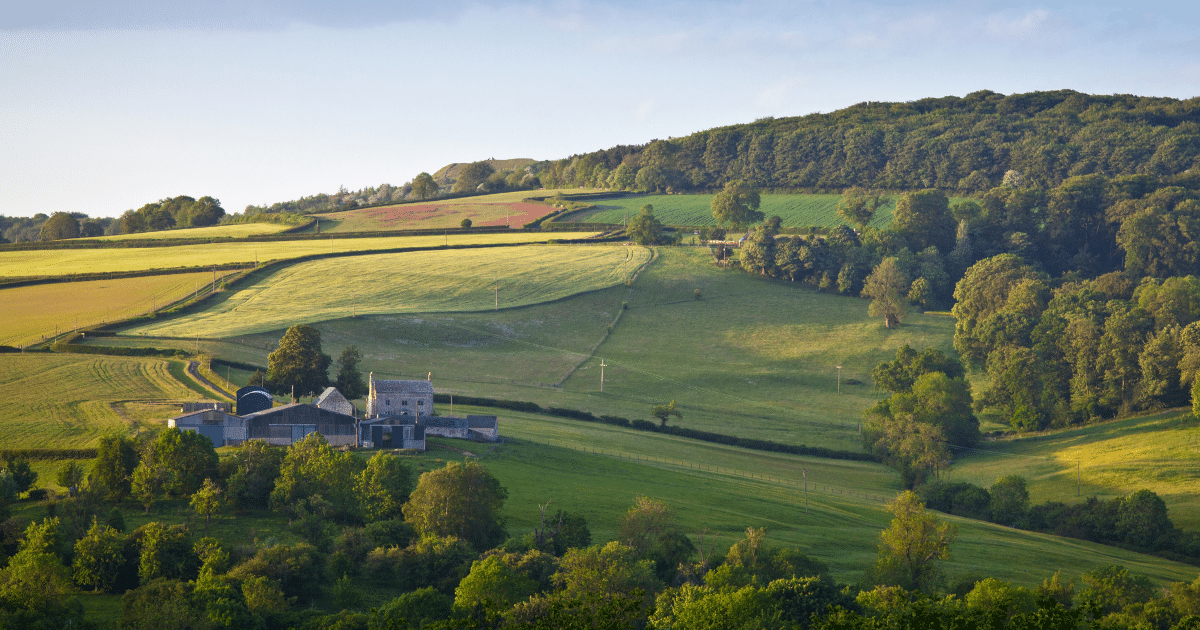 Rolling countryside farm in the Cotswolds with lush green fields and trees