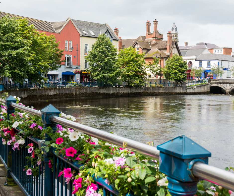 Photo of springtime in Sligo City, Ireland, featuring lush green hills, blooming trees, and a view of the city nestled below Benbulben mountain.