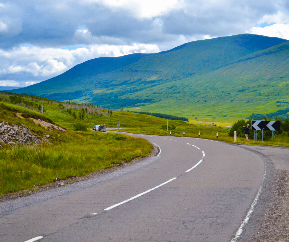 Scenic road winding through the Scottish Highlands with mountains and open landscape
