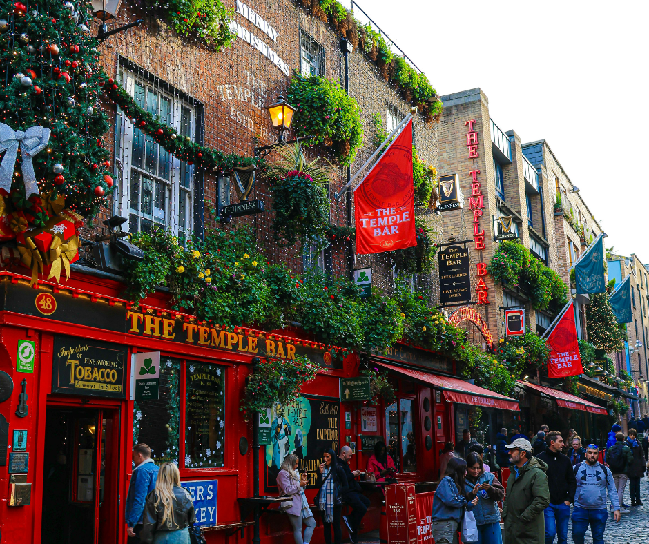 Christmas lights and festive decorations adorning The Temple Bar pub in Dublin, Ireland, with garlands, twinkling lights, and holiday crowds on a winter evening.