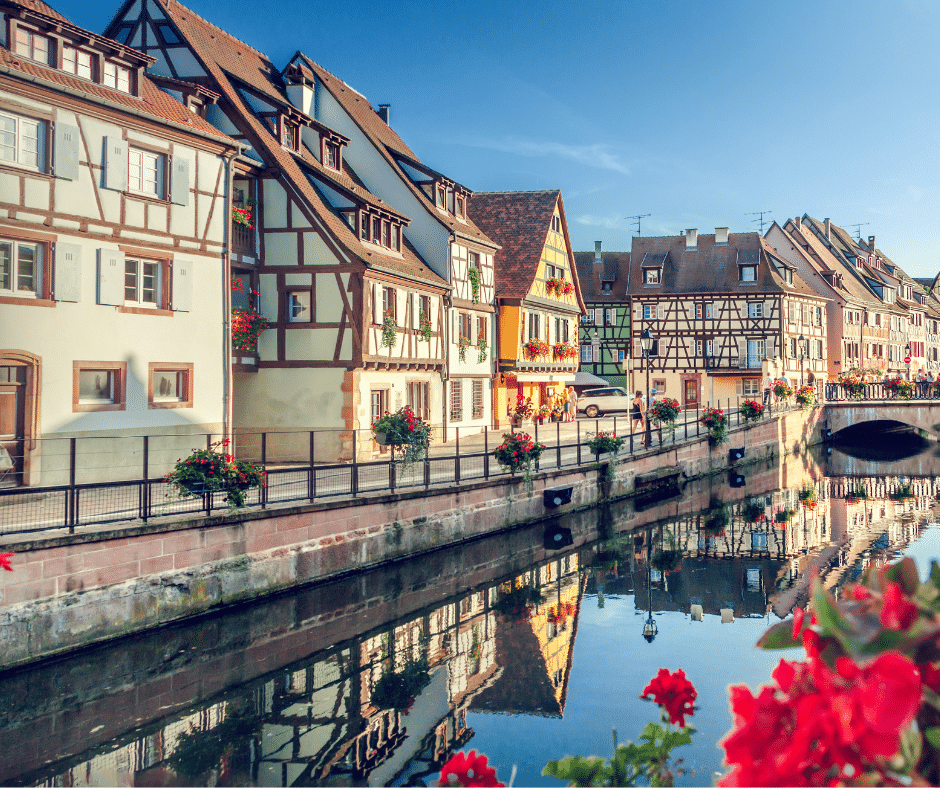 Flower-lined canal in Colmar’s La Petite Venice with pastel half-timbered houses in Alsace, France