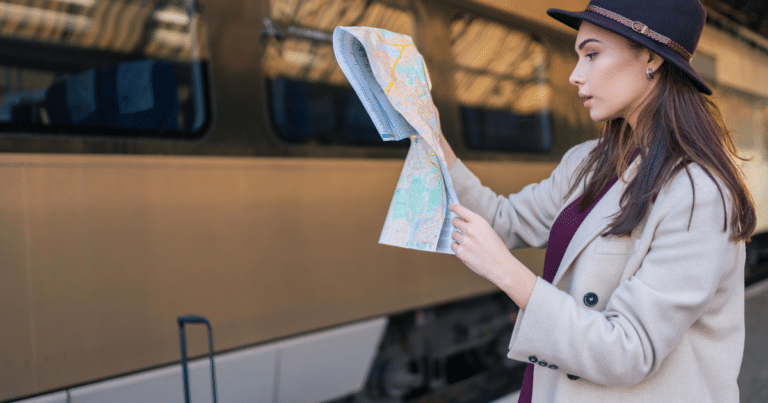 Traveler reading a map beside a train in Europe while planning a multi-city itinerary