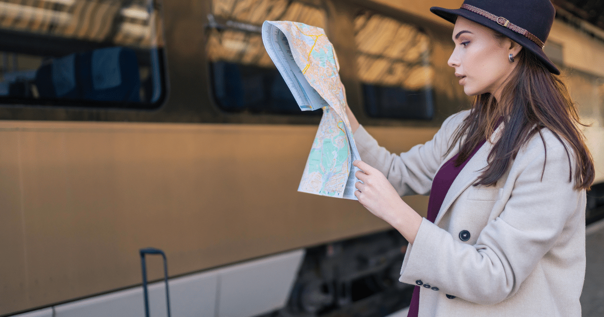 Traveler reading a map beside a train in Europe while planning a multi-city itinerary